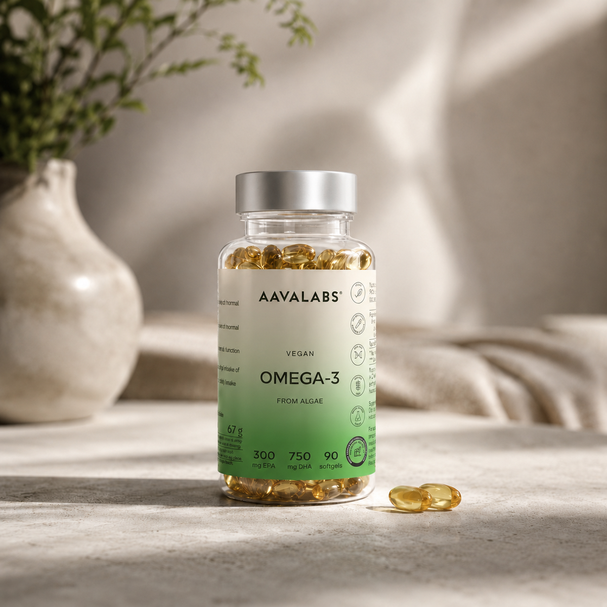 Clear plastic bottle of yellow softgels labeled AAVALABS VEGAN OMEGA-3 FROM ALGAE with two capsules on a stone surface.
